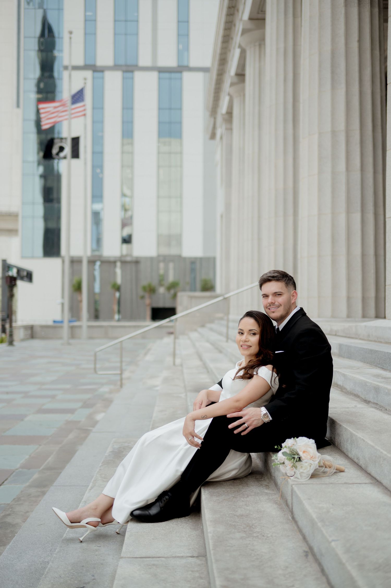 A bride and groom share romantic poses on grand marble steps of a courthouse building.