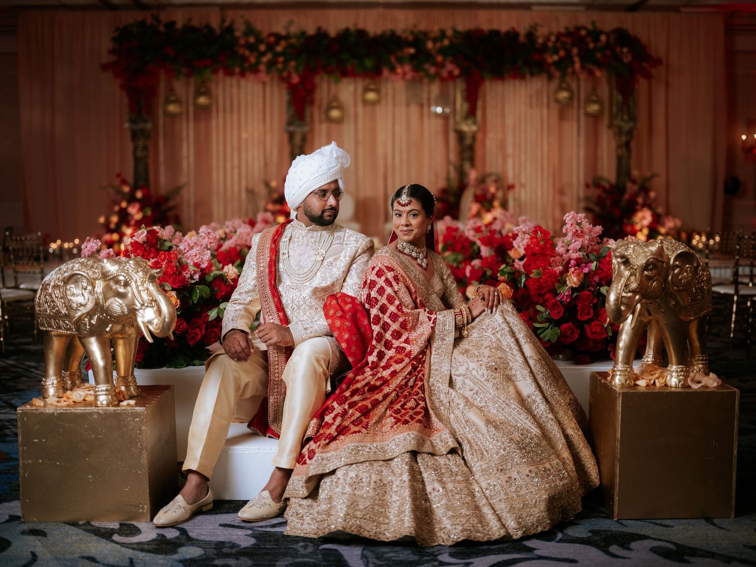 A lavish Indian wedding reception venue decorated with red roses and illuminated by warm candlelight and chandeliers. Picnic Fishtown