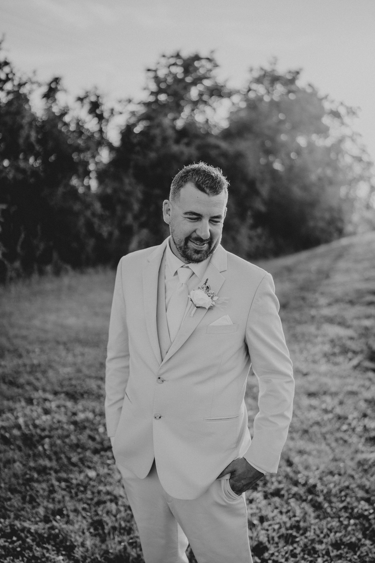 A person wearing an all white suit poses outdoors in black and white photography.