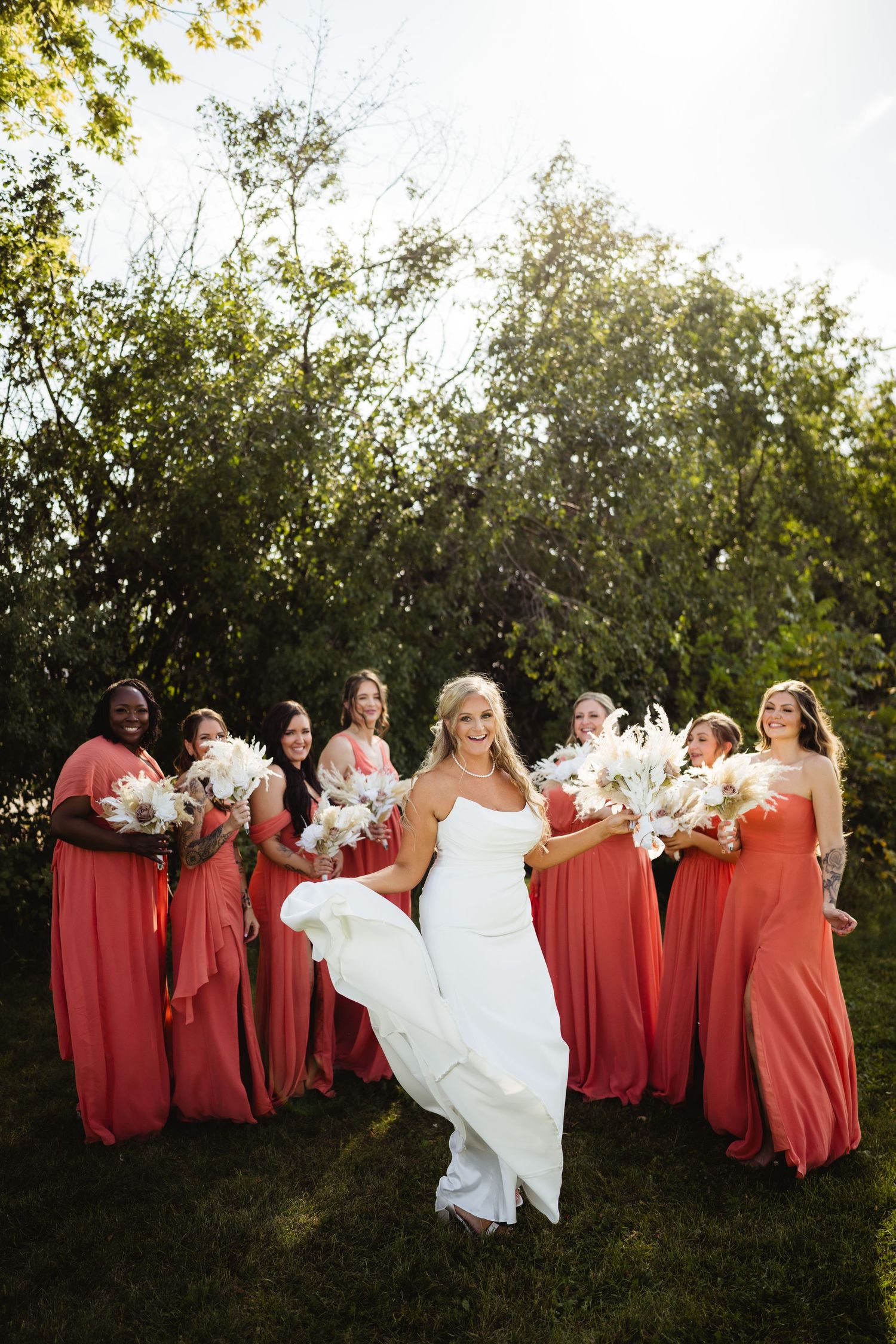 A group of bridesmaids in red dresses pose together with a bride in white during an outdoor photo session.
