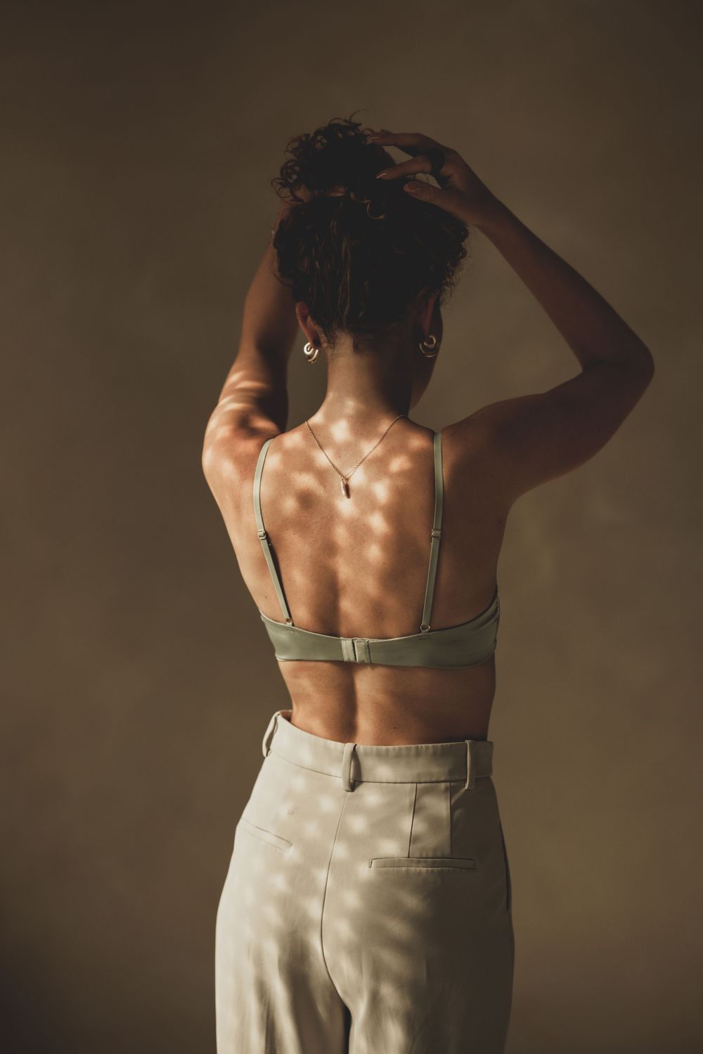Studio fashion sequence showing back details of clothing in warm lighting.