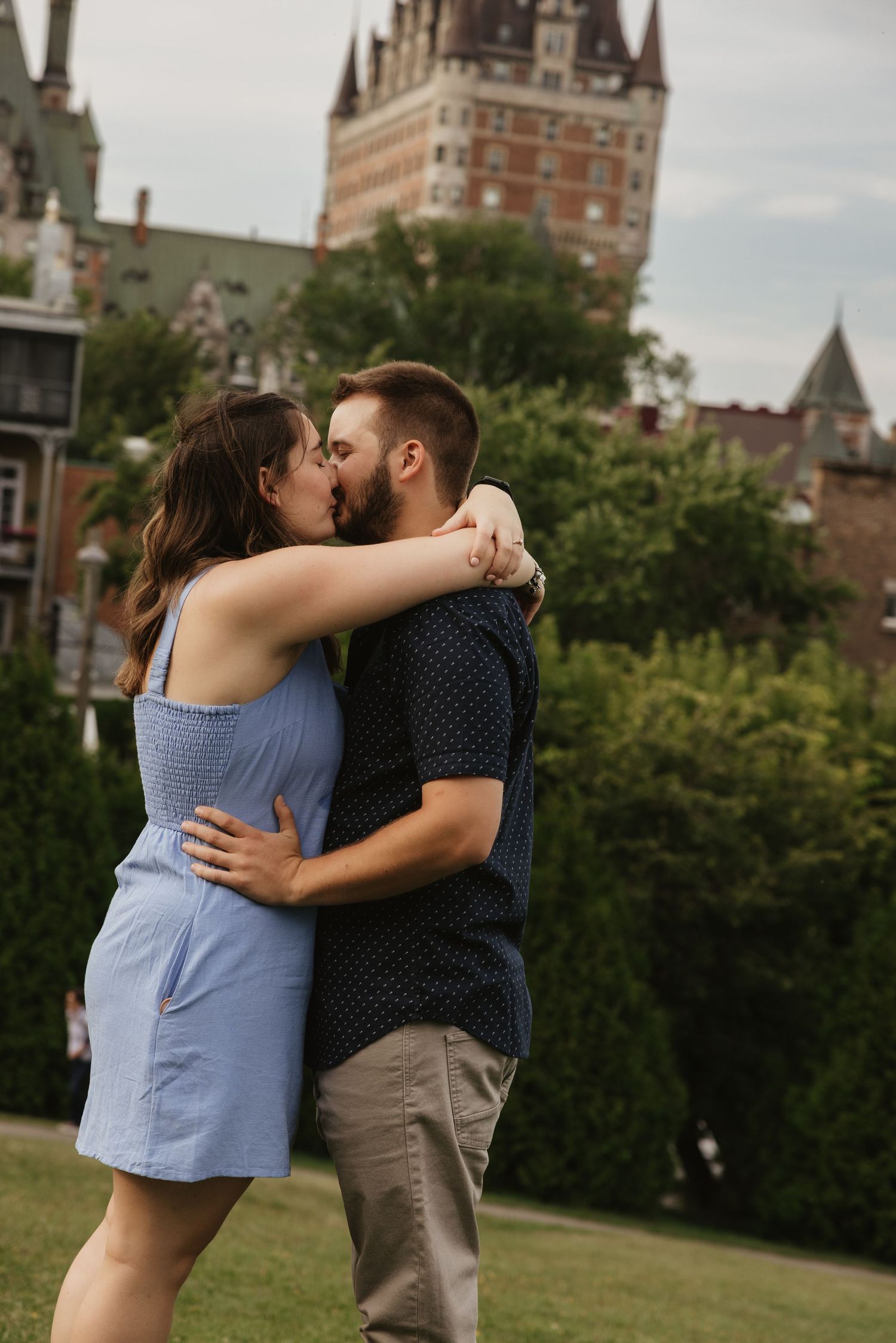 A romantic couple shares a tender kiss in front of historic Chateau Frontenac in Quebec City.