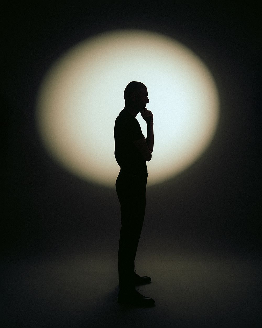Minimalist silhouette sequence showing a standing figure against an oval light background.