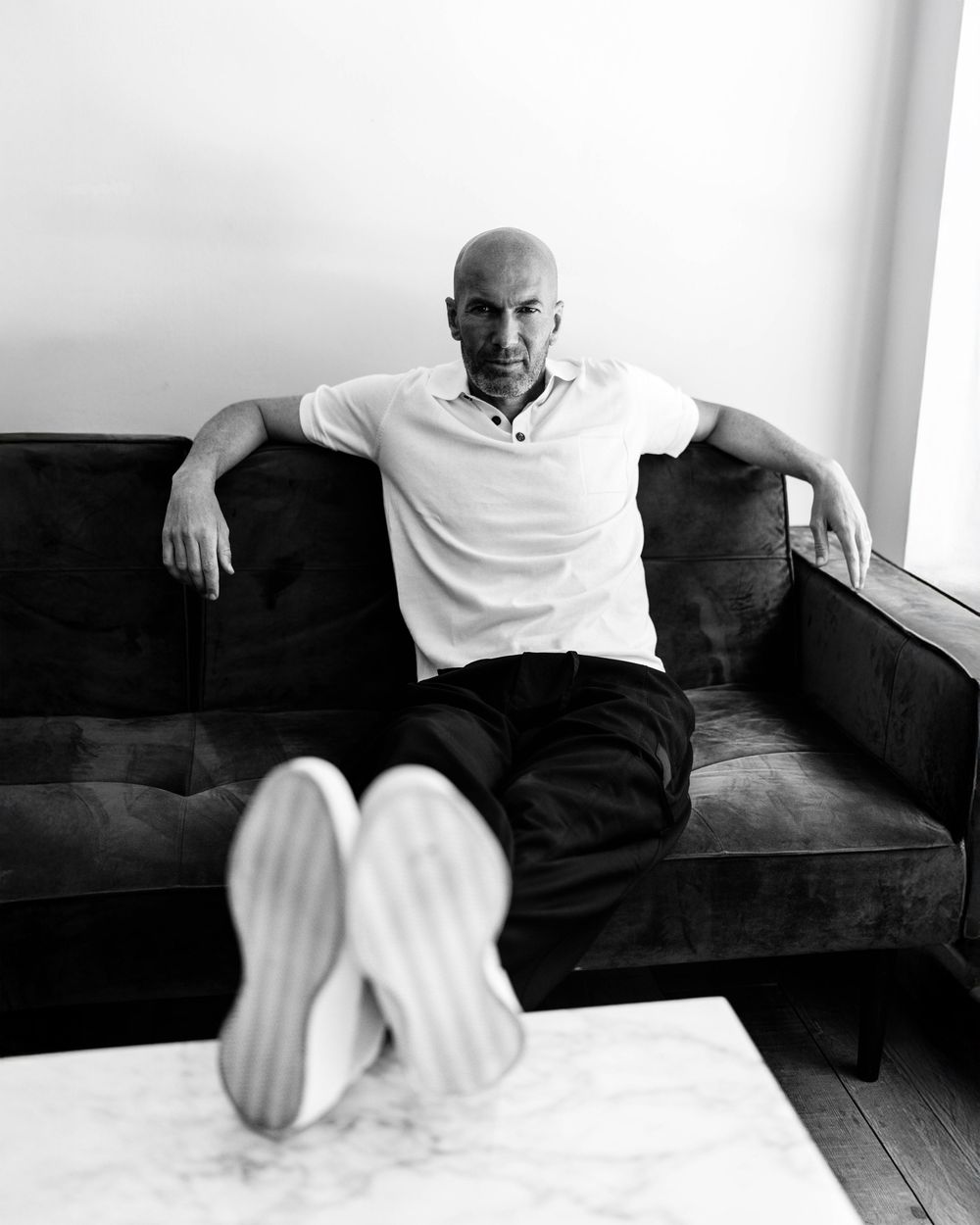 Black and white series showing someone relaxing on a dark couch in casual attire.