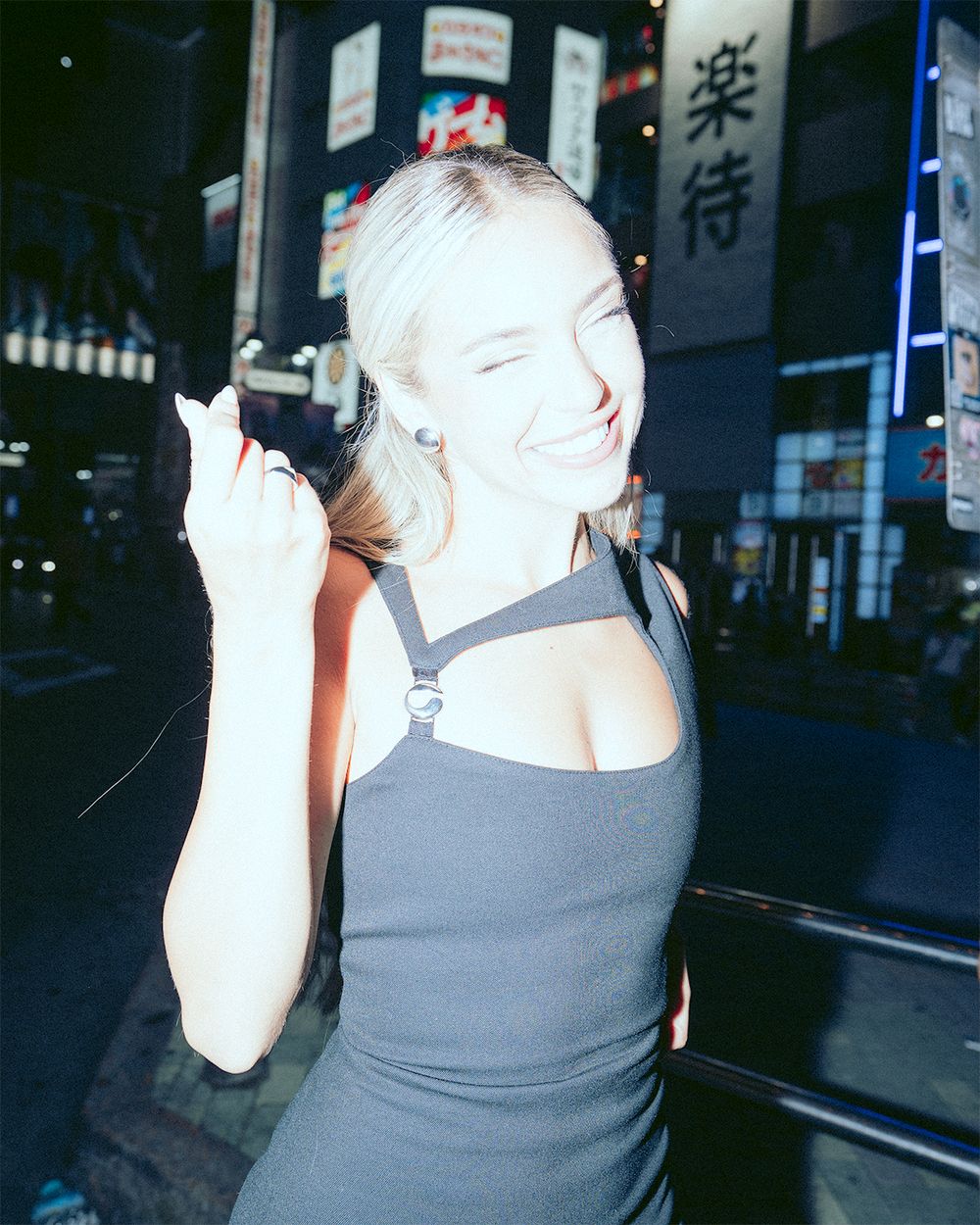 A person in a gray tank top walking on a dark city street at night.