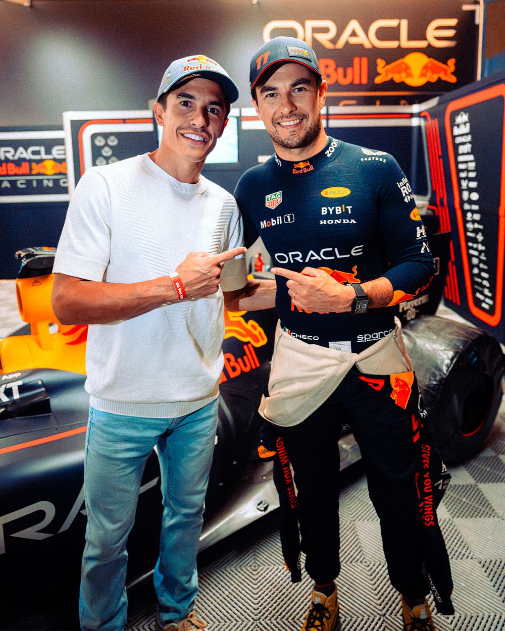 Formula 1 fans pose together for photos in Oracle Red Bull Racing team merchandise at a racing event.