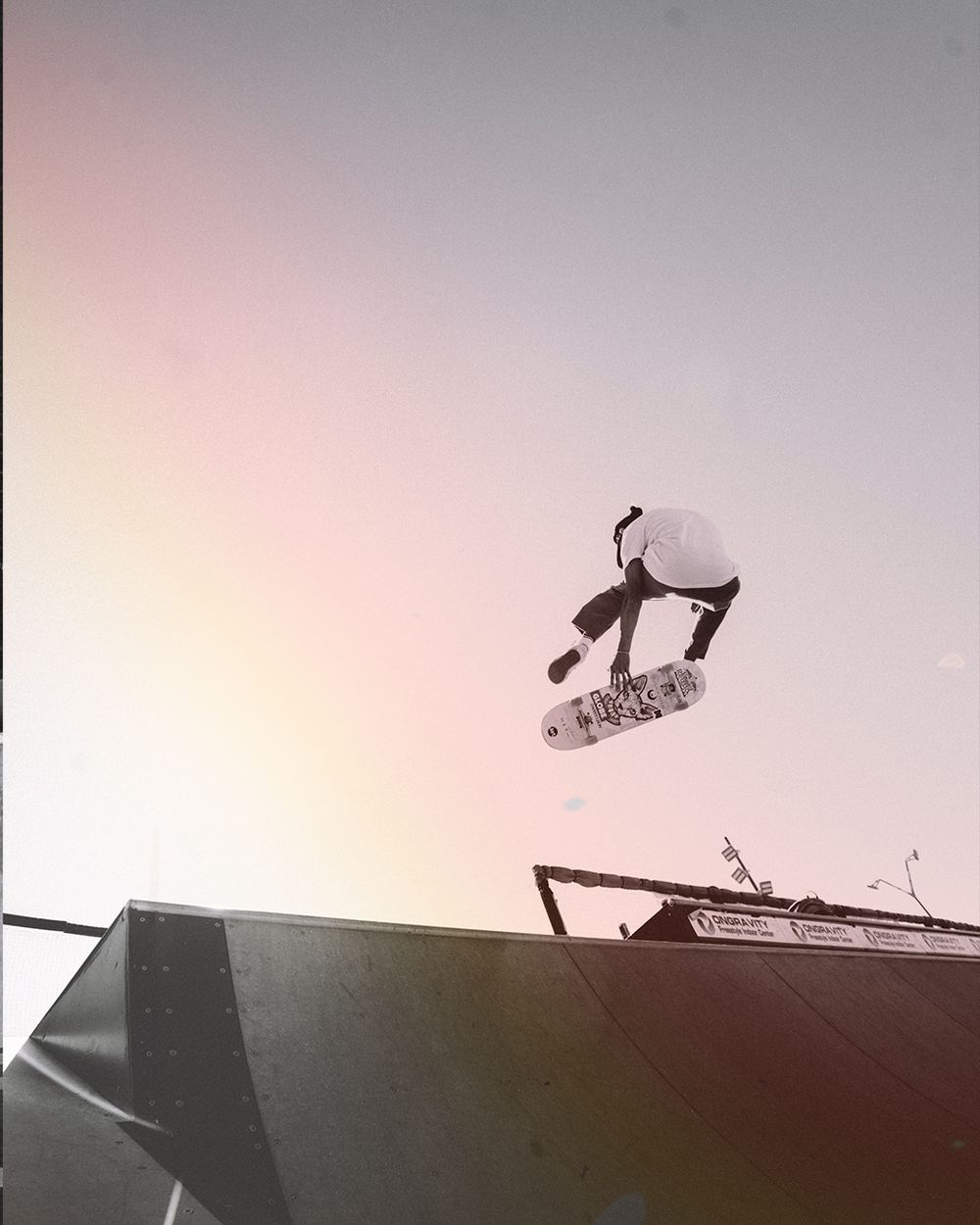 A sequence of silhouettes showing a bird landing on a rooftop against a gradient sky at sunset.