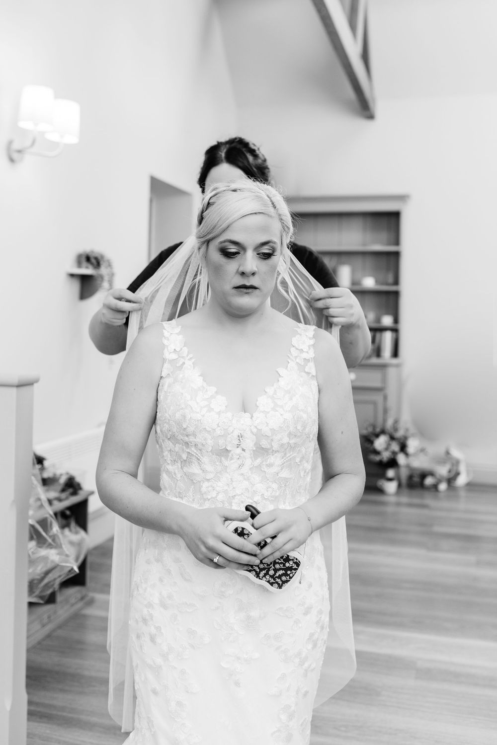 Wedding dress detail showing delicate white lace and beading against a light background.