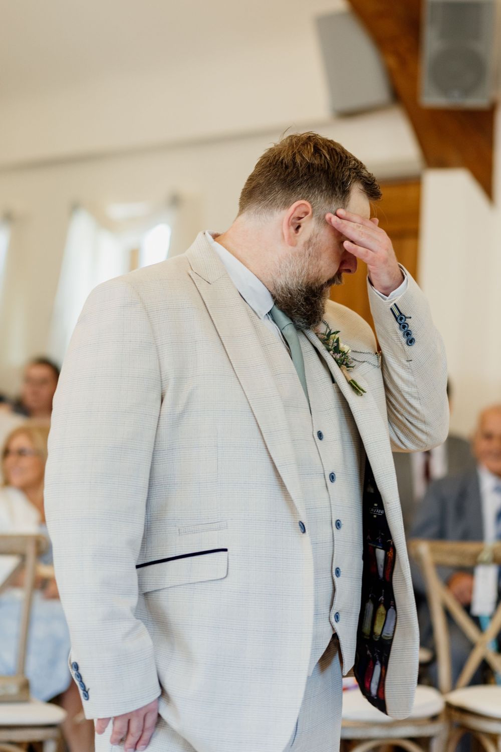 Groomsmen in light gray suits standing in line during a formal wedding ceremony.