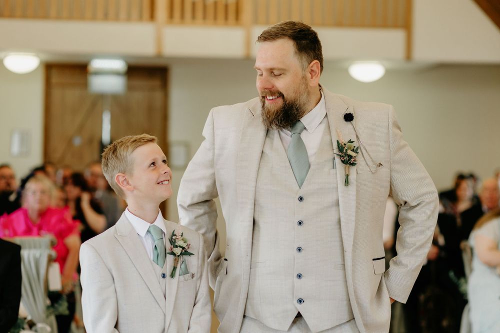 Four candid moments from a wedding ceremony showing joyful reactions and interactions in a light-filled indoor venue.