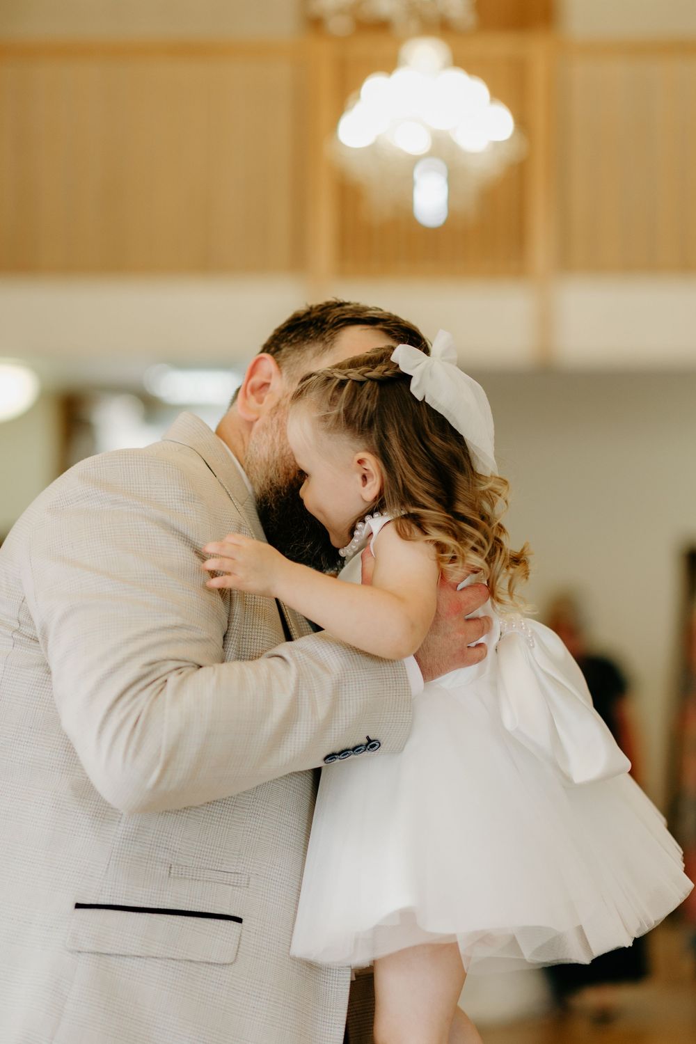 Five sequential photos show a tender kiss between a bride in white and groom in beige at an elegant indoor venue.