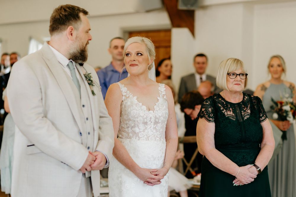 Guests looking on with joy during a wedding ceremony in a rustic indoor venue.