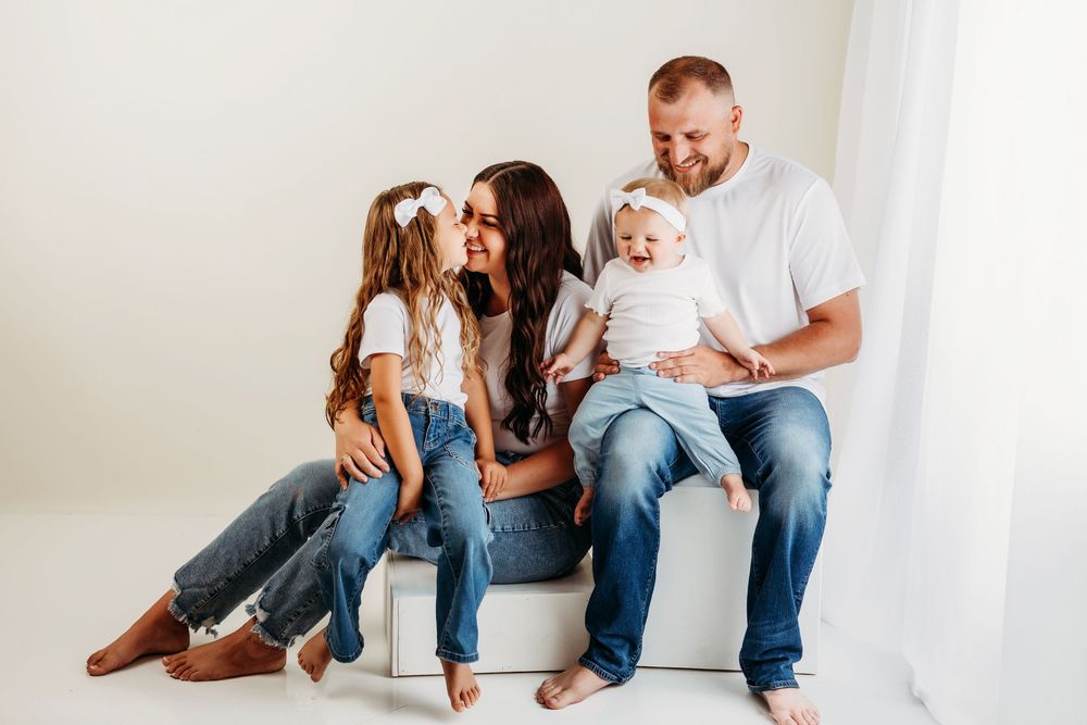 Candid moment captured of family lounging together against white background in coordinated casual wear.