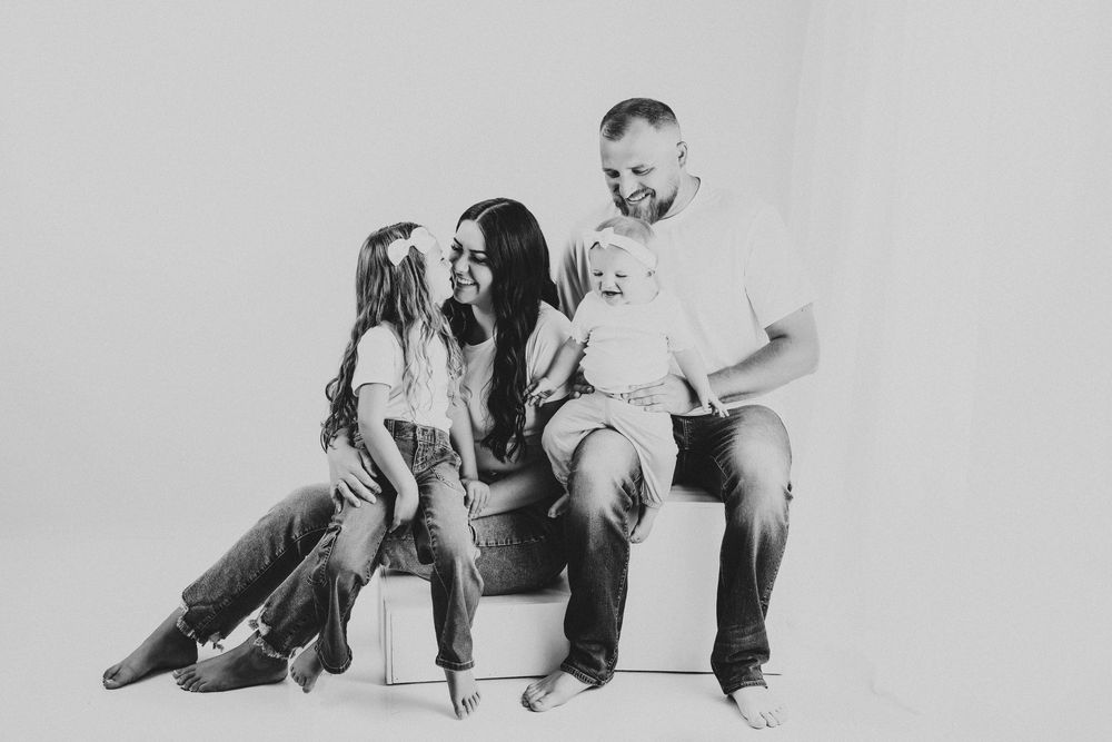 Black and white portrait of a family sharing a joyful moment while seated together.