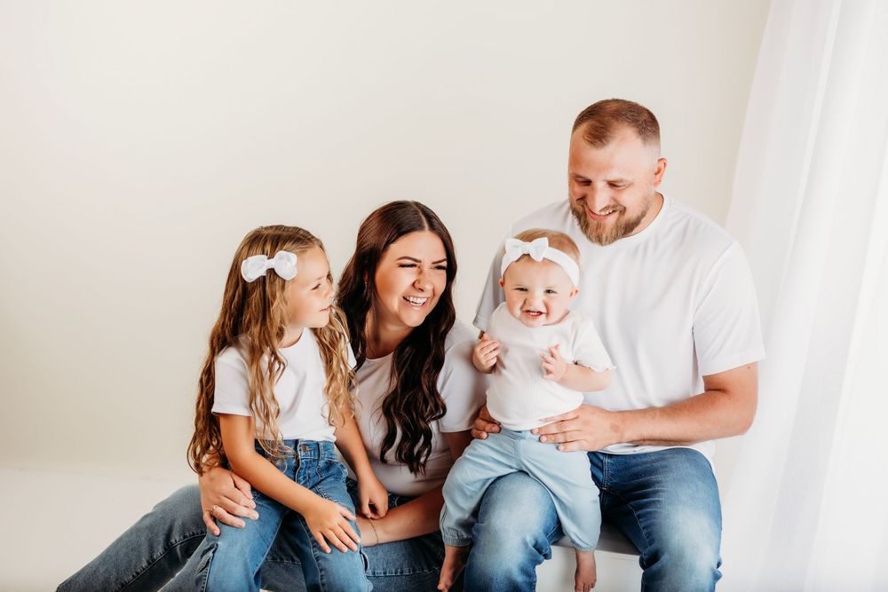 Candid family moment with everyone laughing together against a white backdrop.