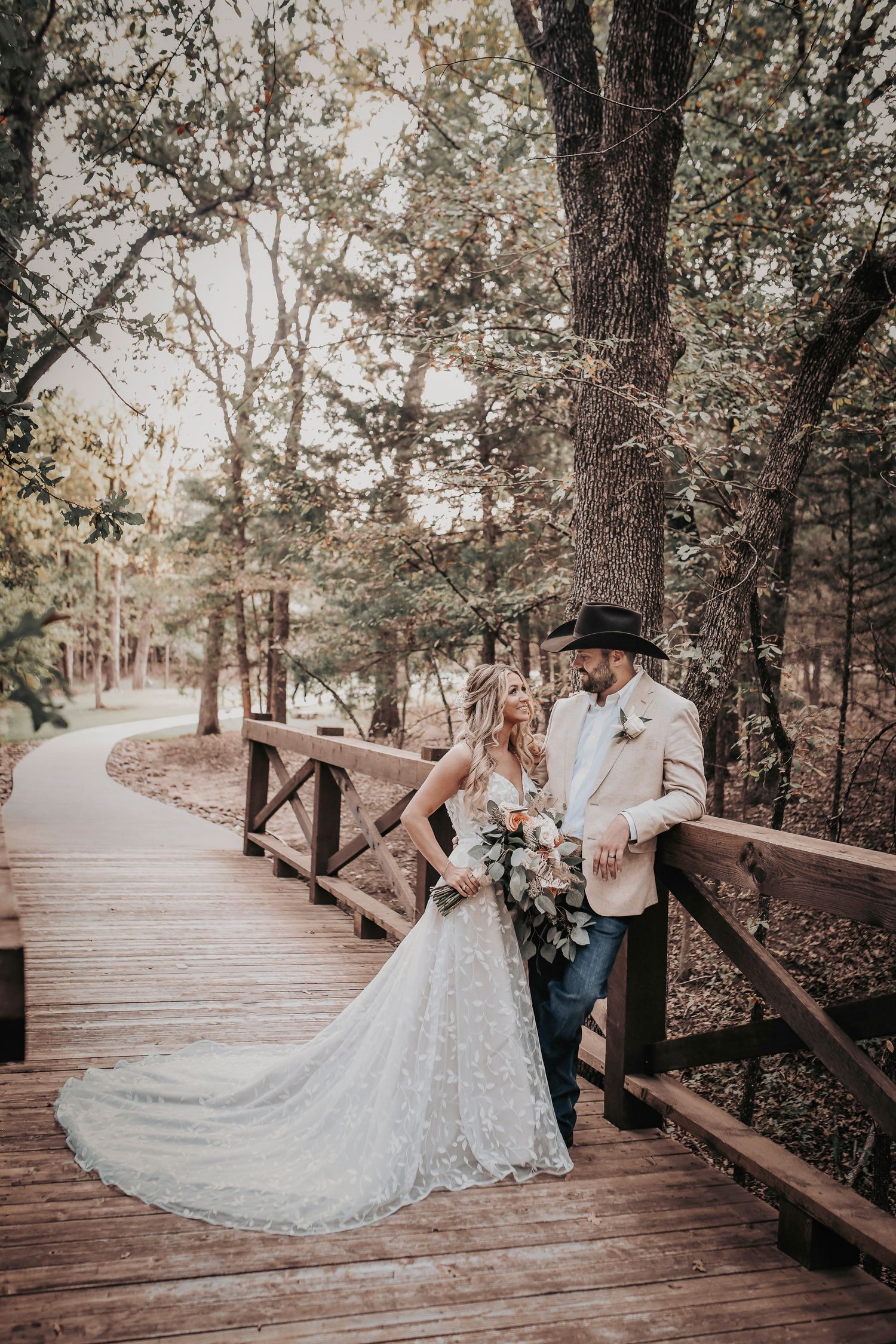 Bride and groom holding hands on rustic wooden bridge at Whispering Oaks Wedding Venue