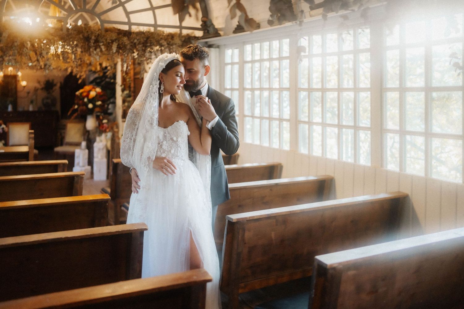 Newlyweds share intimate moments inside a vintage red car during their wedding photoshoot.