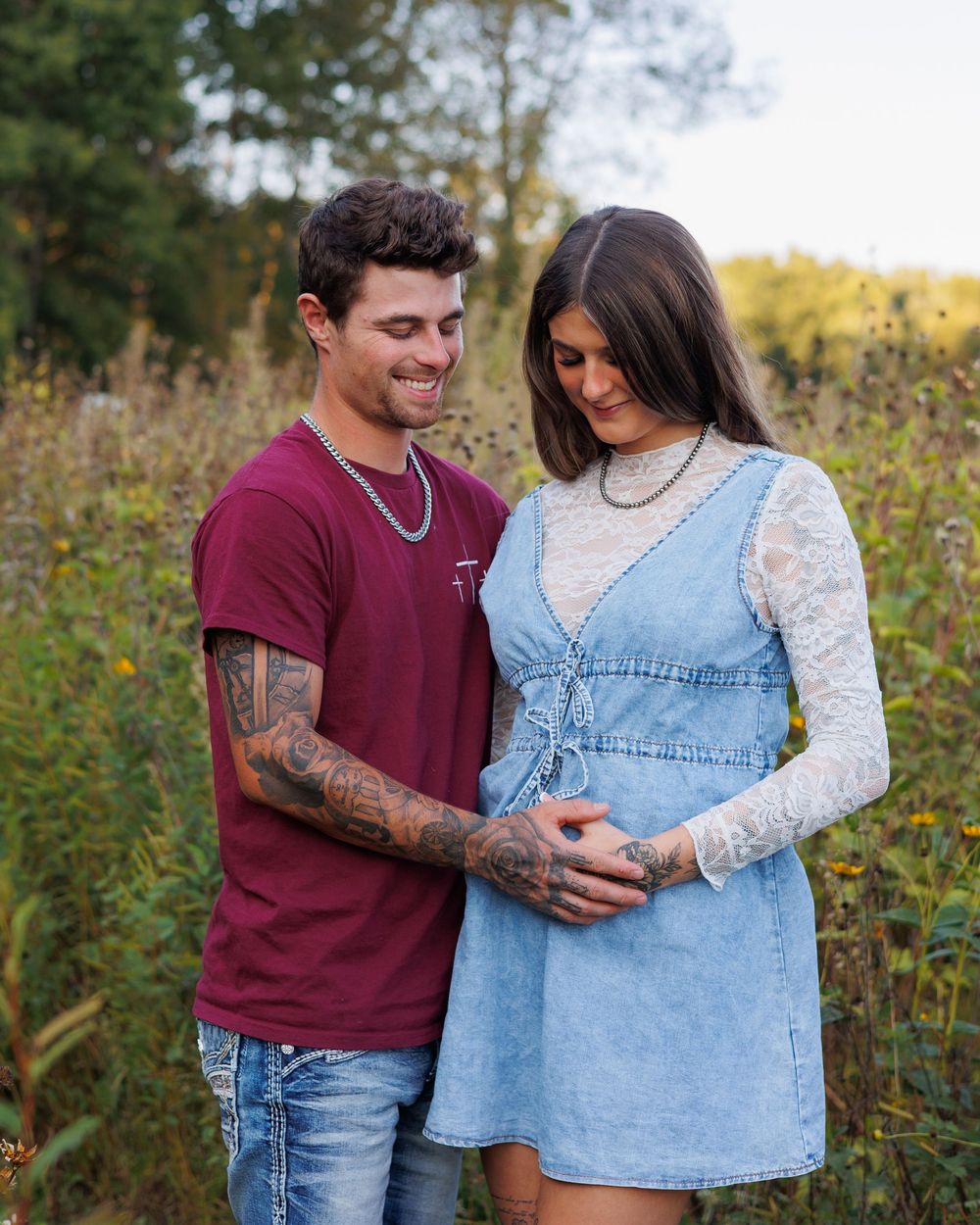 A couple embraces in a field of wildflowers during a romantic outdoor photoshoot.