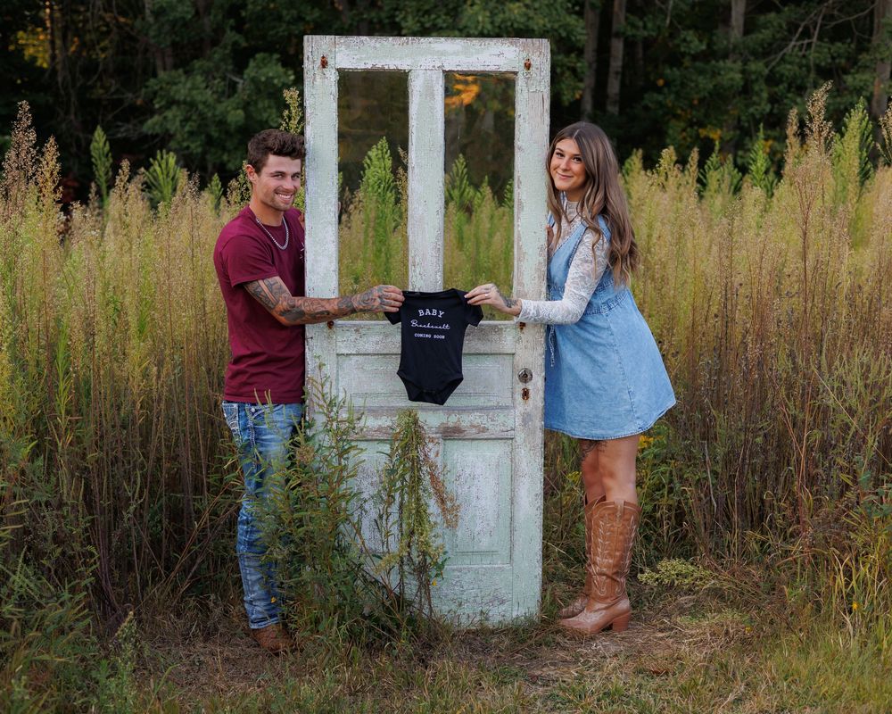 A rustic white door stands among tall grass and wildflowers in an outdoor setting during golden hour.