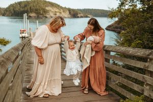 Family portrait session on a rustic wooden dock overlooking a scenic lake and mountains.