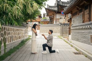 A romantic proposal moment at a traditional Korean temple courtyard with stone walls.