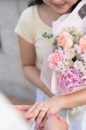 Close up of hands holding a delicate pink and white floral bouquet.