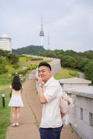 Candid moment at Seoul Tower with walking path and stone wall.