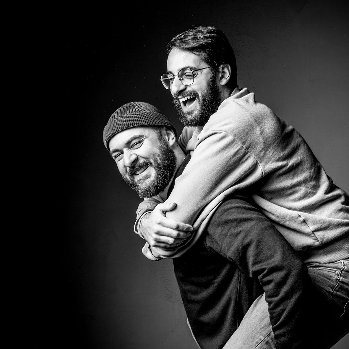 Schwarz weiß Portrait eines Paares im Fotosudio in Gelsenkirchen Hassel - er hat seinen Partner im Huckepack auf dem Rücken Studiofotograf