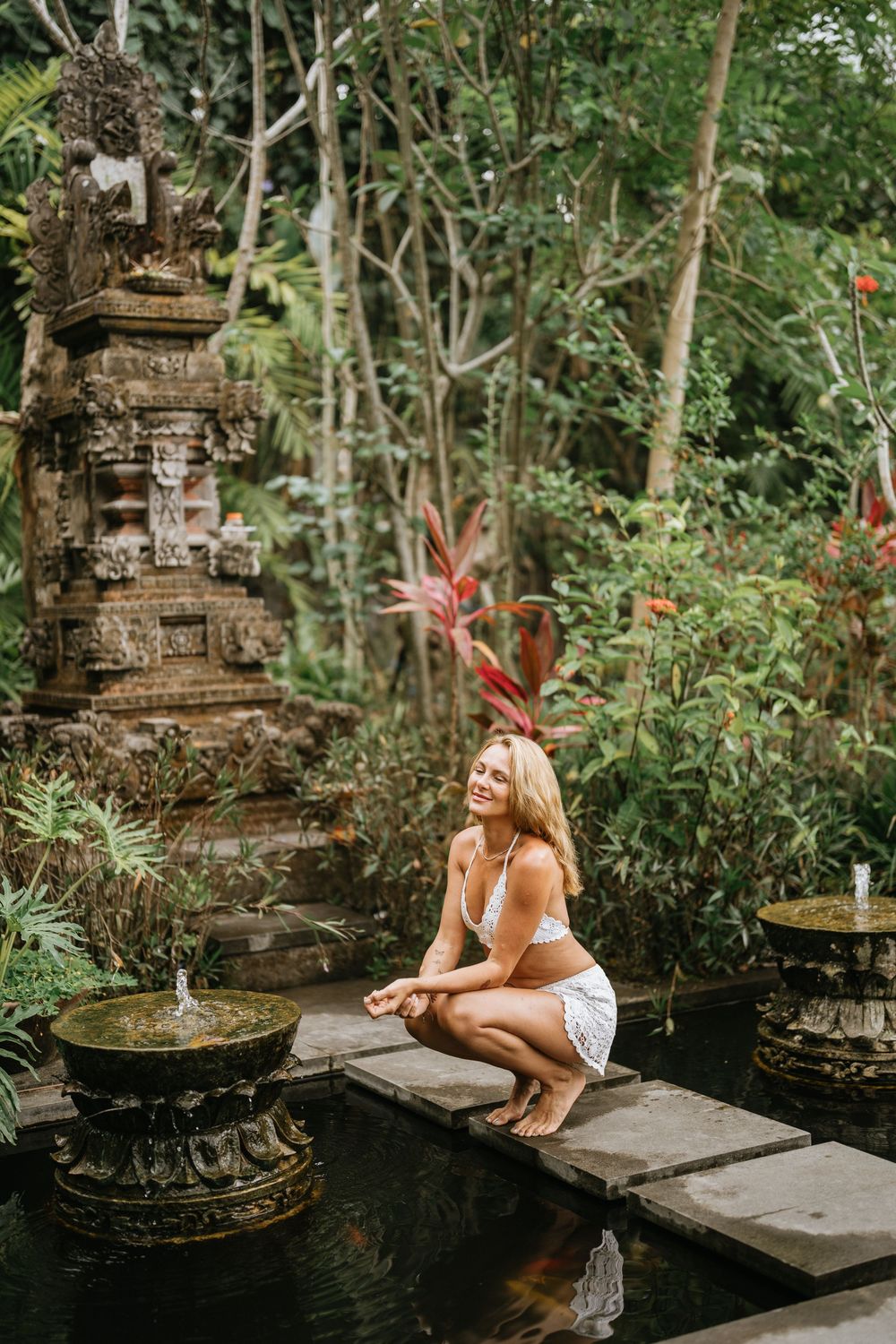 Ancient stone temple fountains surrounded by lush tropical gardens and koi ponds in Bali.