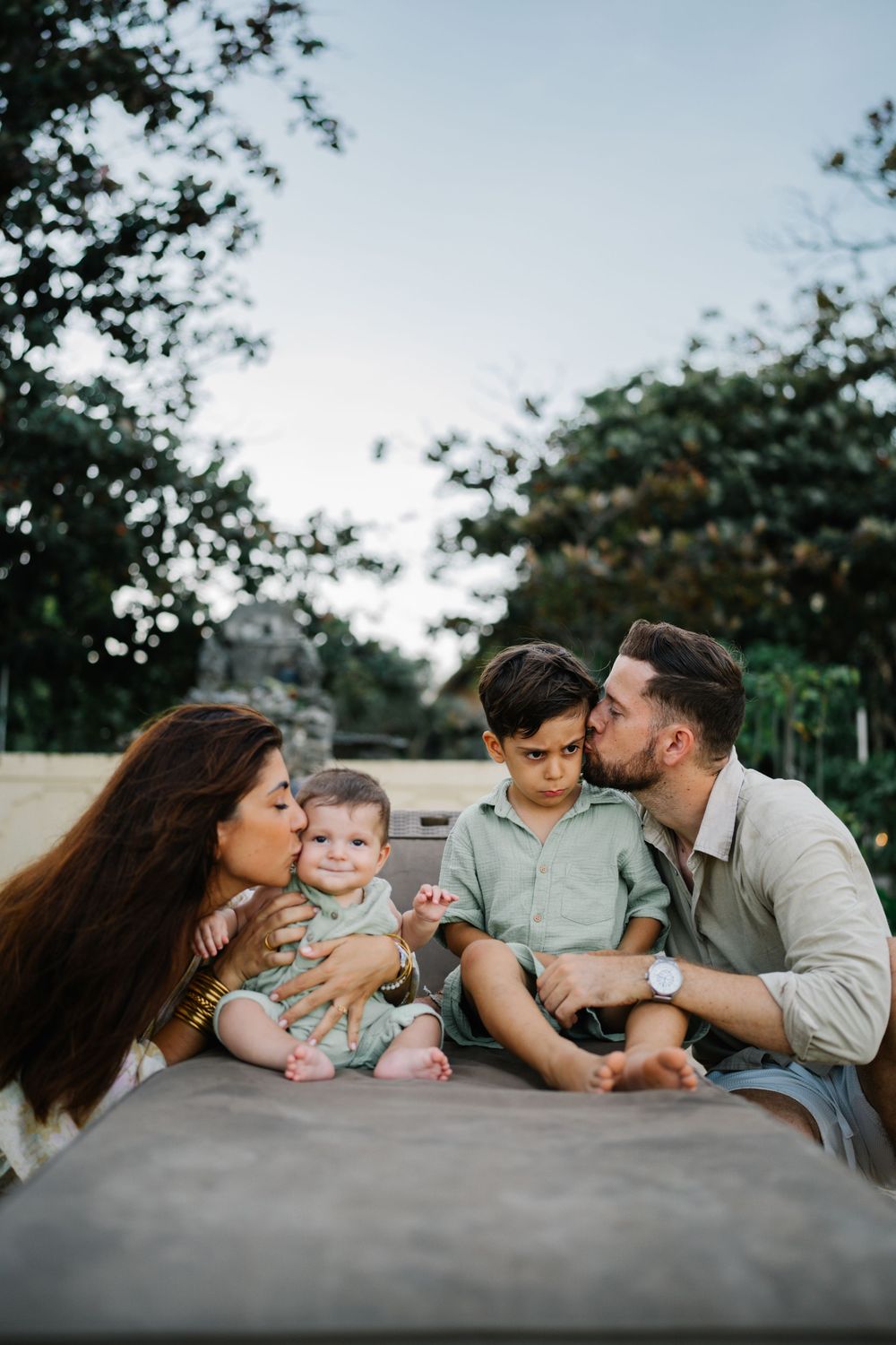 An intimate family portrait captured during a casual outdoor photoshoot.