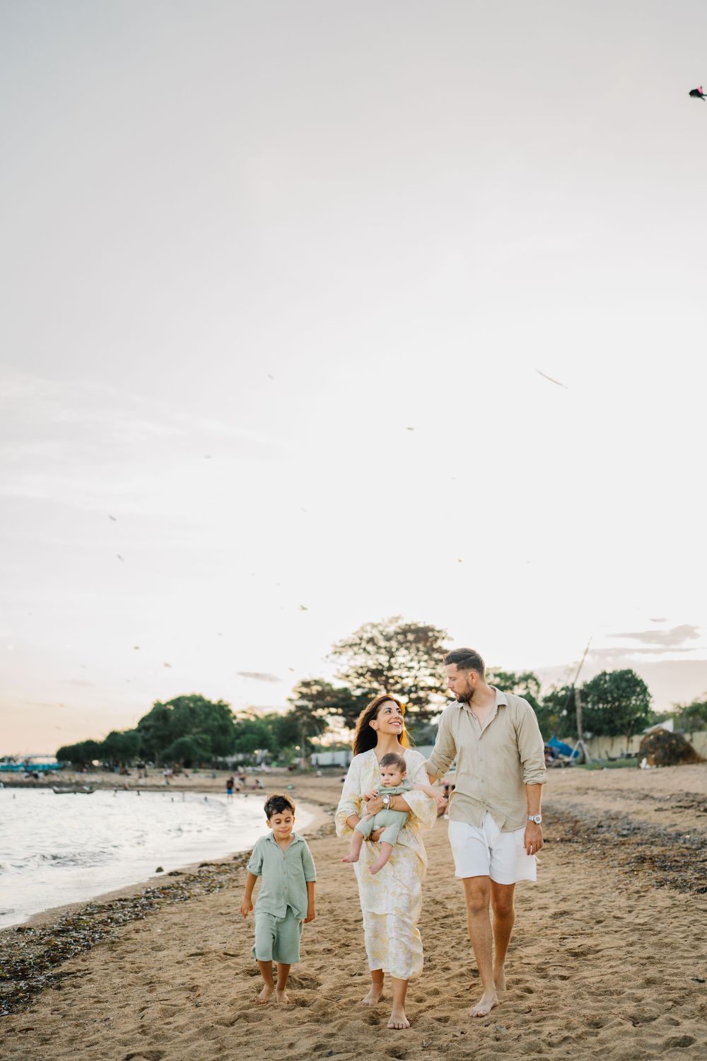 A family takes a sunset stroll along a peaceful beach shoreline.