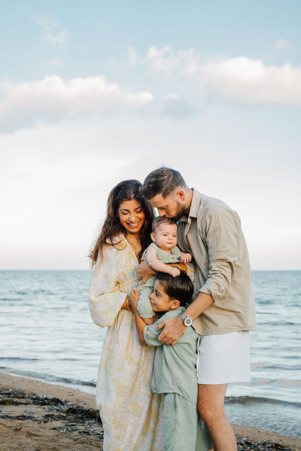 A family shares an intimate moment together on a beach at sunset.