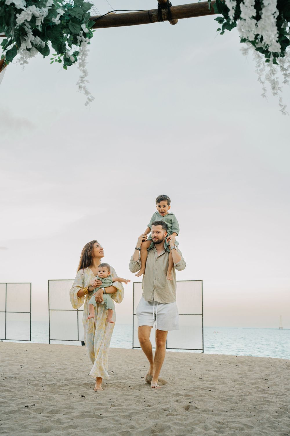 Family playing and running together on a sandy beach at sunset.