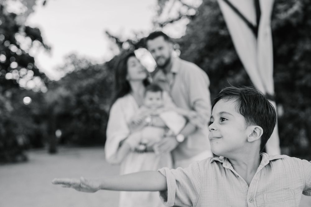 A series of black and white photos showing joyful family moments outdoors.