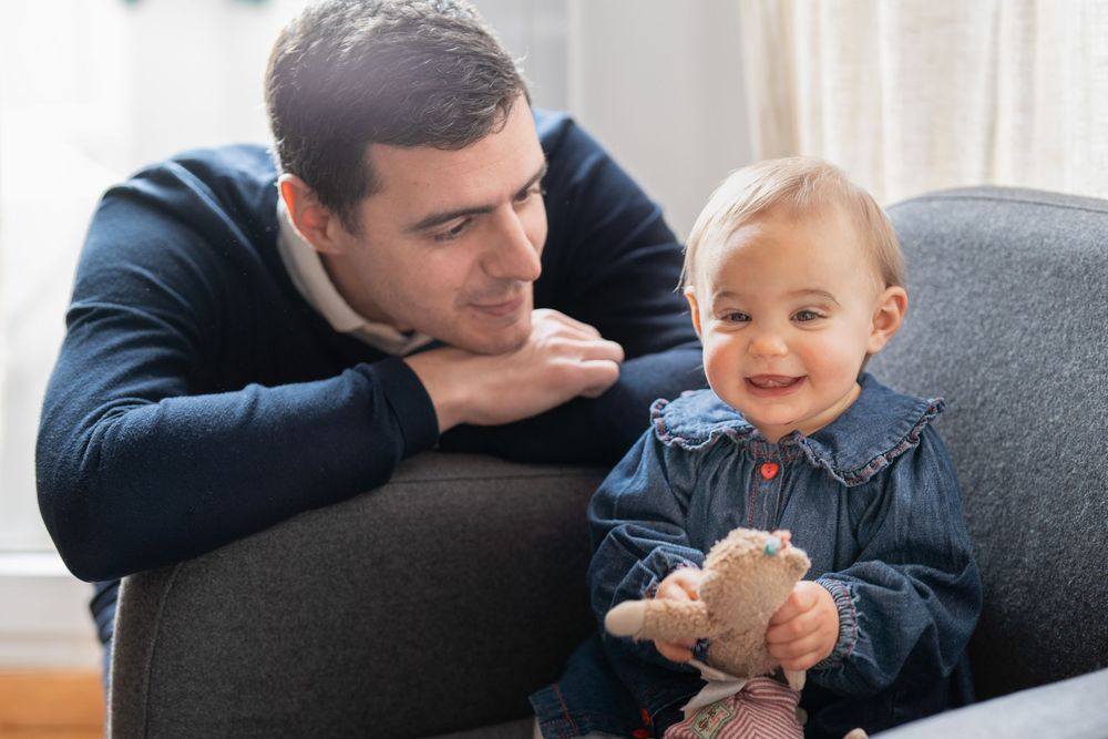 Papa qui regarde sa fille avec tendresse, dans leur salon, à Rueil-Malmaison