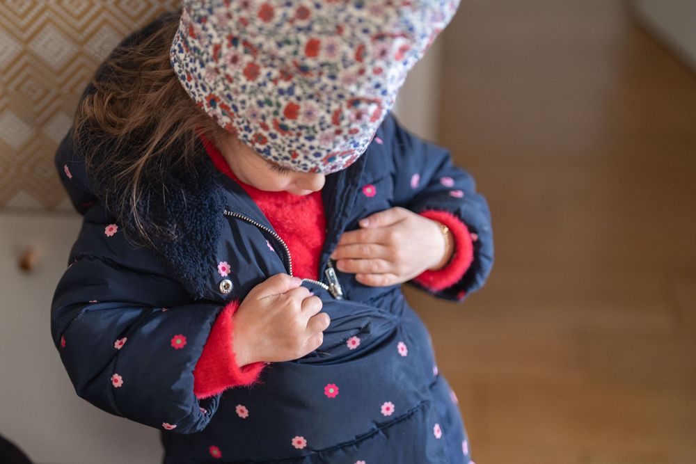 Petite fille qui met son manteau, à Rueil-Malmaison