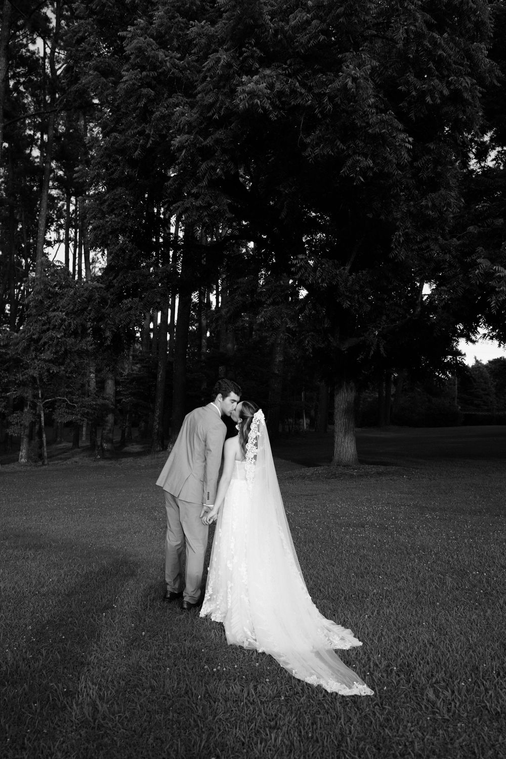 A romantic black and white series showing newlyweds walking through a tranquil garden setting in elegant wedding attire.