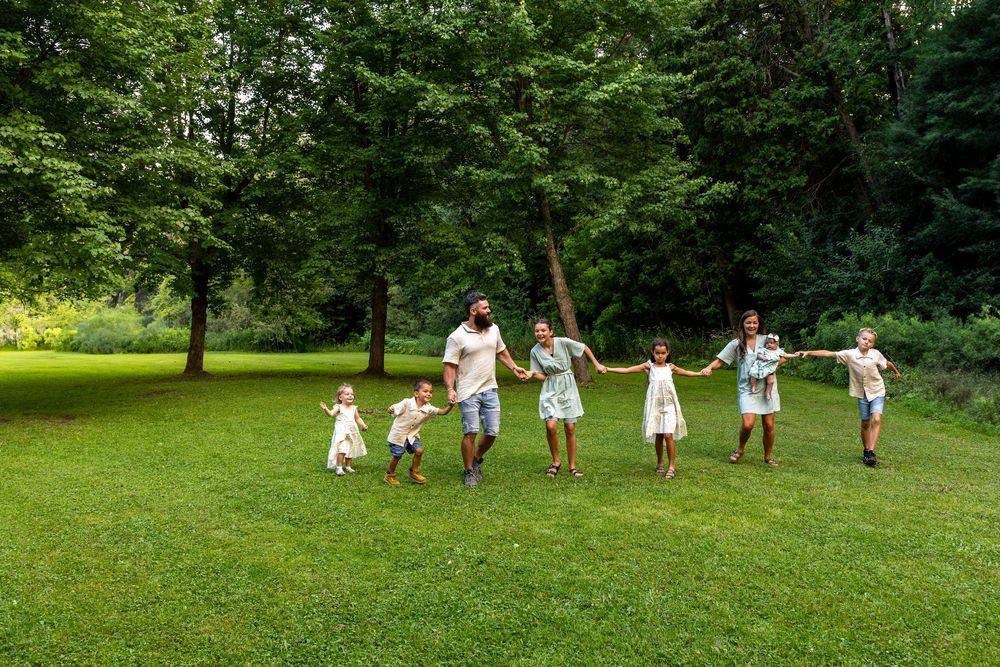 A family of 8 walking through a park on a beautiful late summer evening all stretched out holding hands
