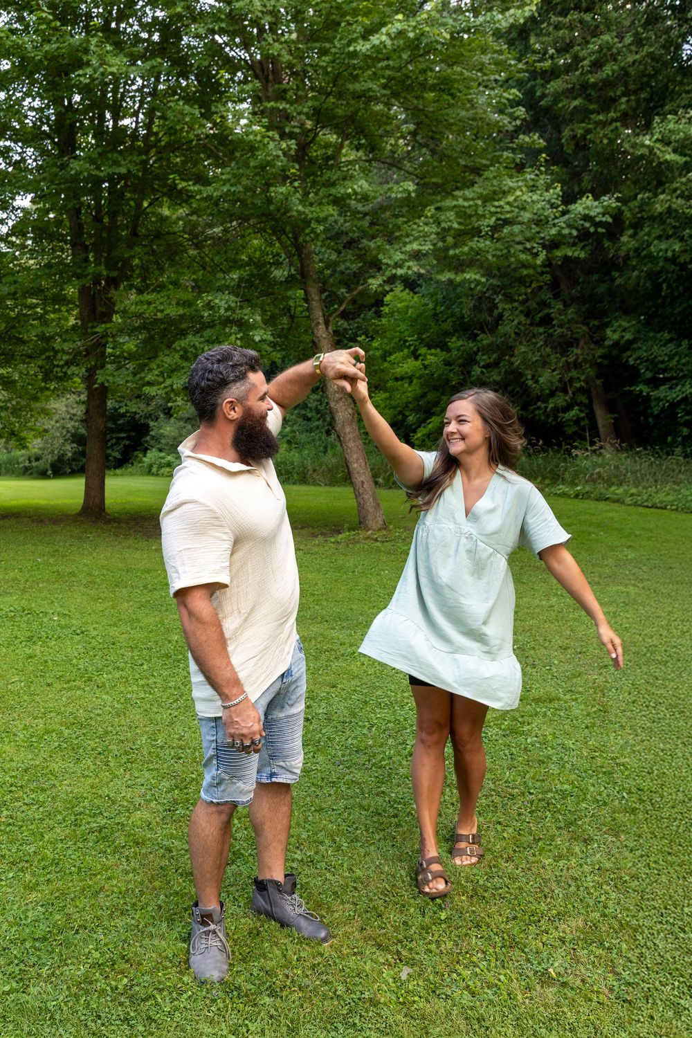 A husband twirling his wife in a flowy dress in a park