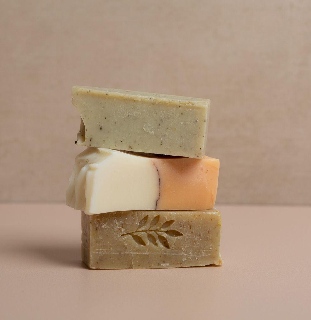 Handmade artisanal soap bars stacked and arranged on beige background.