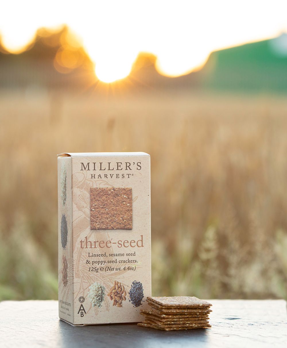 Miller's Harvest three-seed crackers photographed at sunset in wheat field.