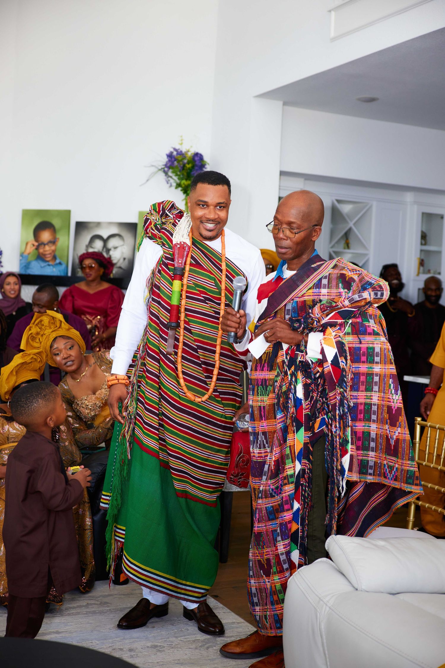 People wearing colorful traditional African clothing and garments celebrate during a joyous gathering.