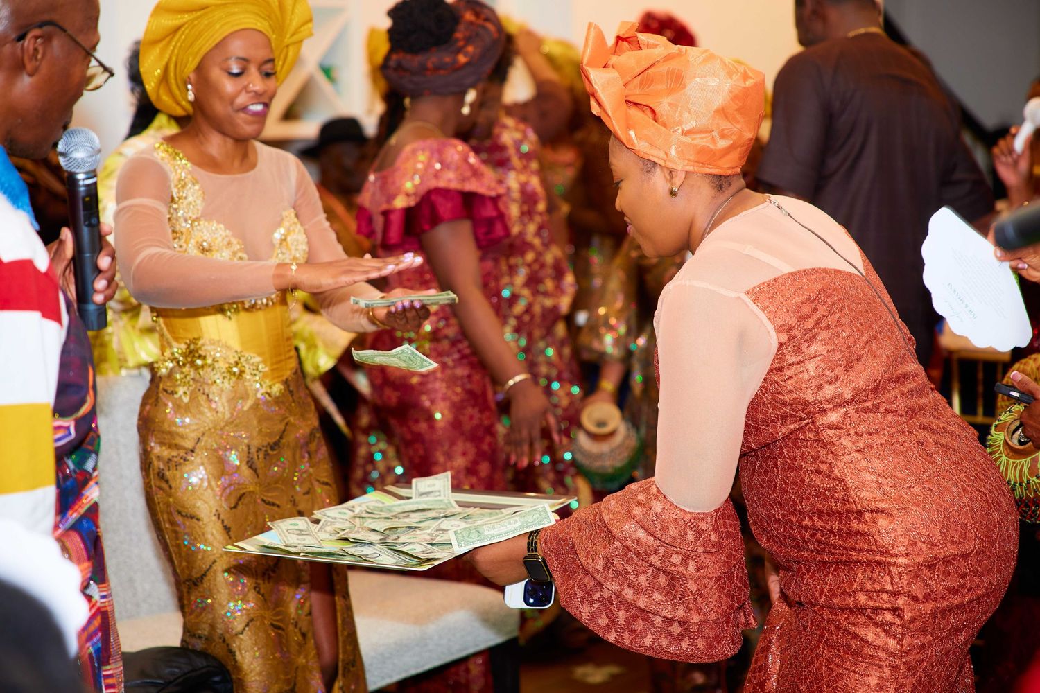 A group of people celebrating at a formal event wearing traditional Nigerian attire in shades of coral and gold.