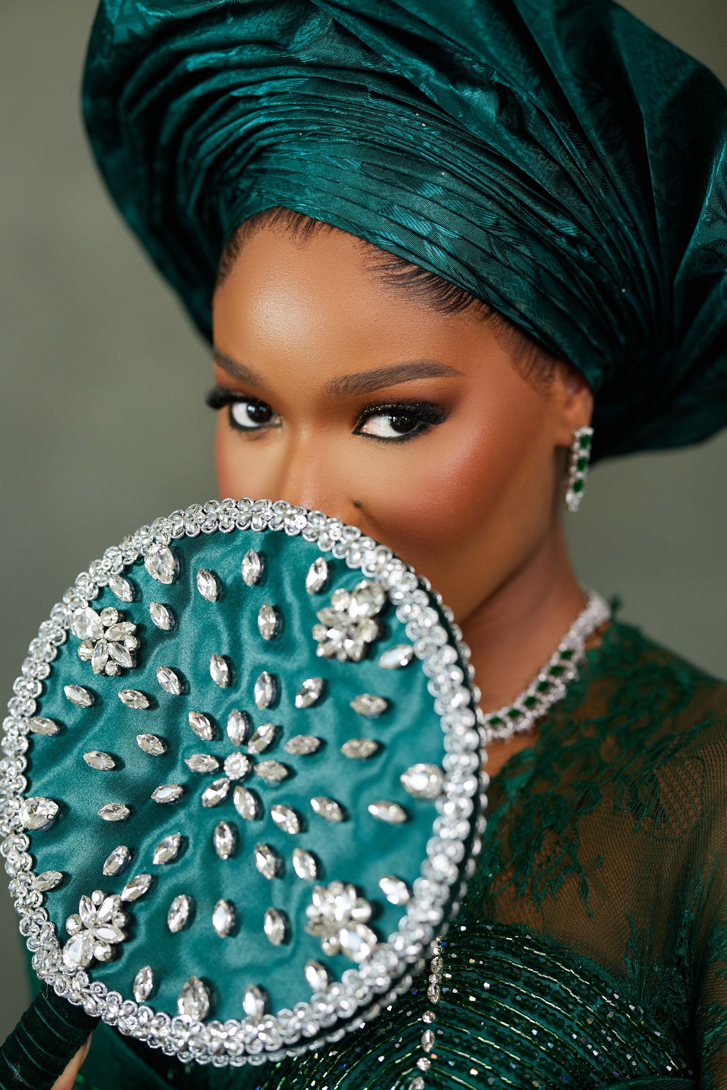 A glamorous teal headpiece with crystal embellishments adorns a fashionable evening look.