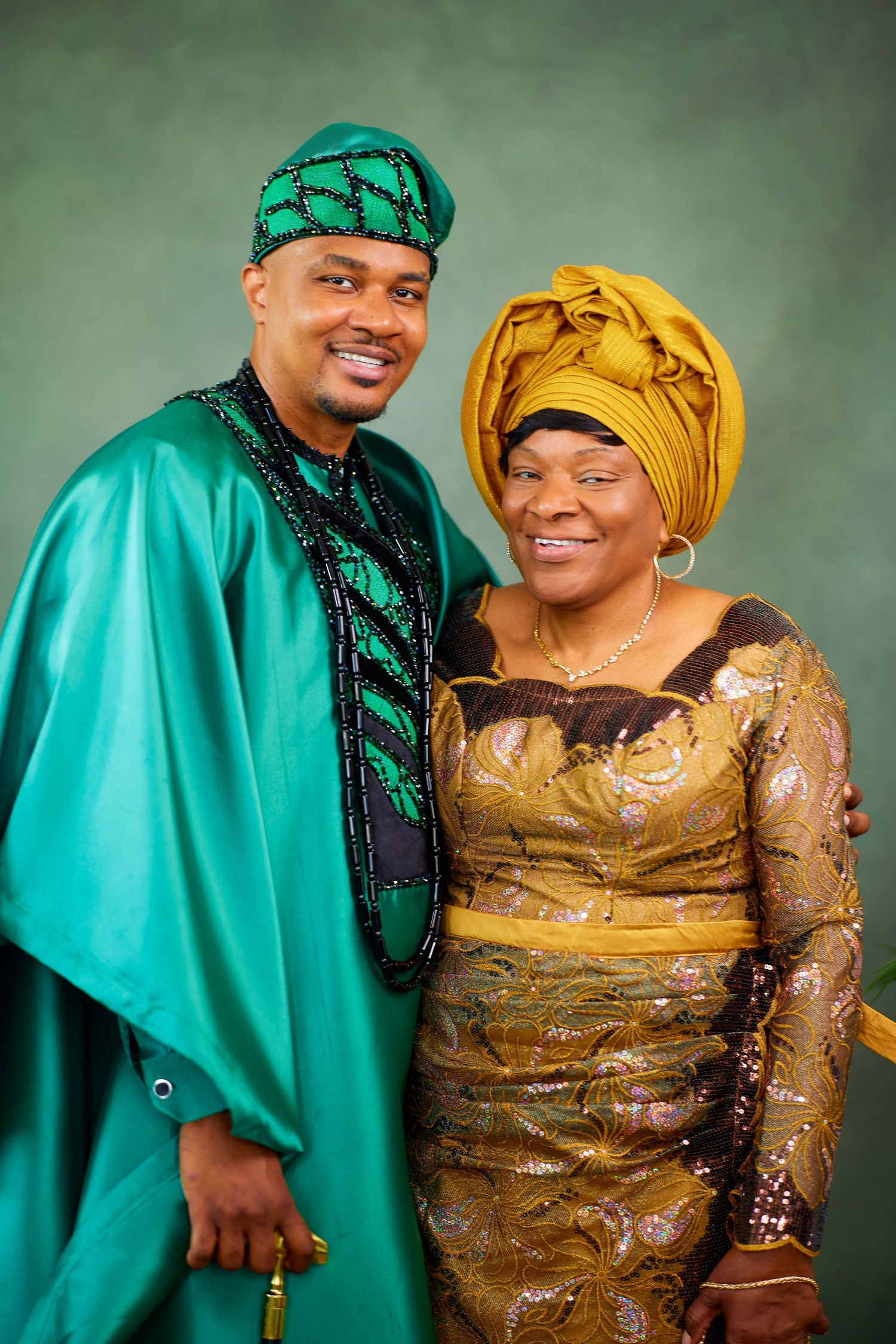 Studio portraits show couple in traditional Nigerian attire with vibrant turquoise agbada and golden gele headwrap and dress.