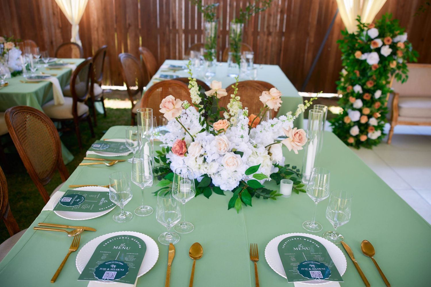 Rustic wooden-walled banquet hall decorated with white floral centerpieces and green table settings for an elegant event.