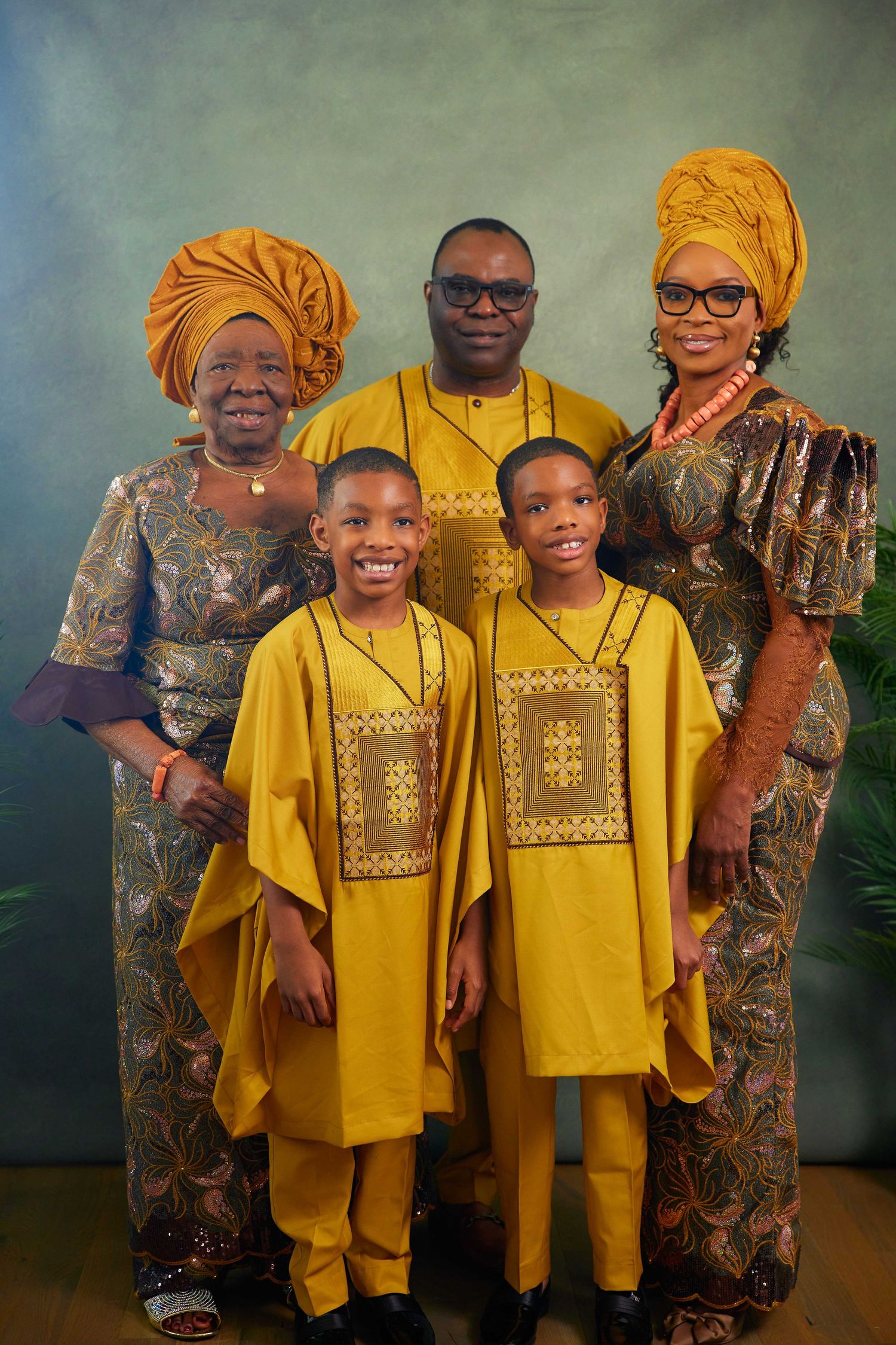 Traditional family group photo featuring matching yellow and brown traditional African attire with cultural designs.
