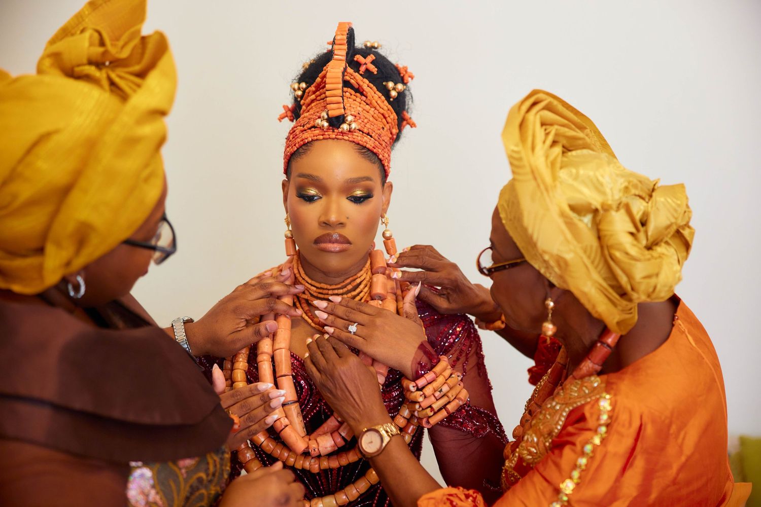 Traditional west African wedding celebration featuring bright orange and yellow traditional attire and cultural accessories.