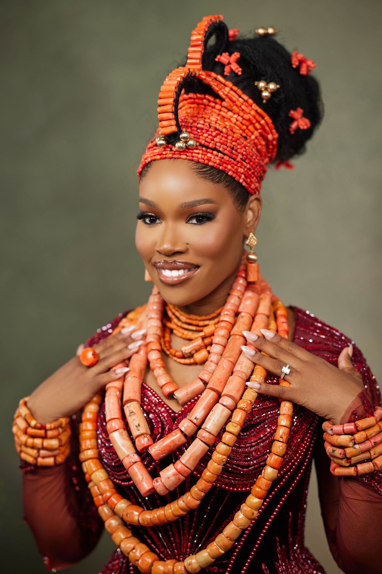 Portrait showcasing traditional Nigerian wedding attire with coral beaded jewelry and dark burgundy dress.