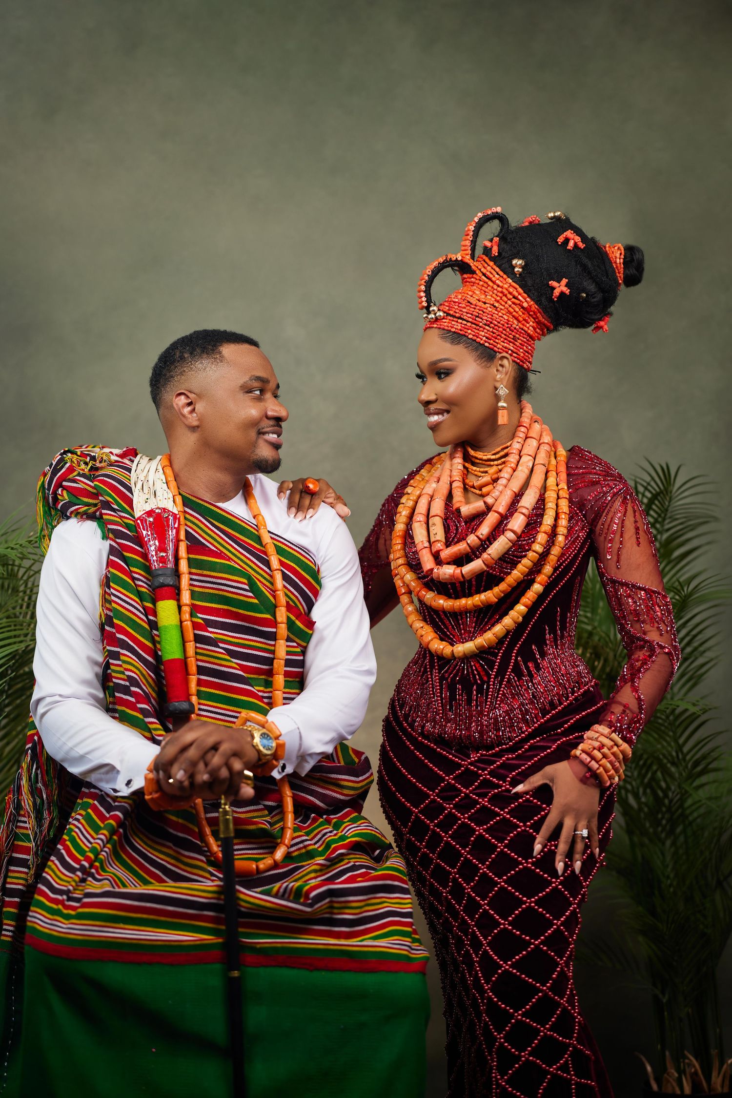Traditional Nigerian couple in colorful attire embracing and laughing during cultural engagement photoshoot.